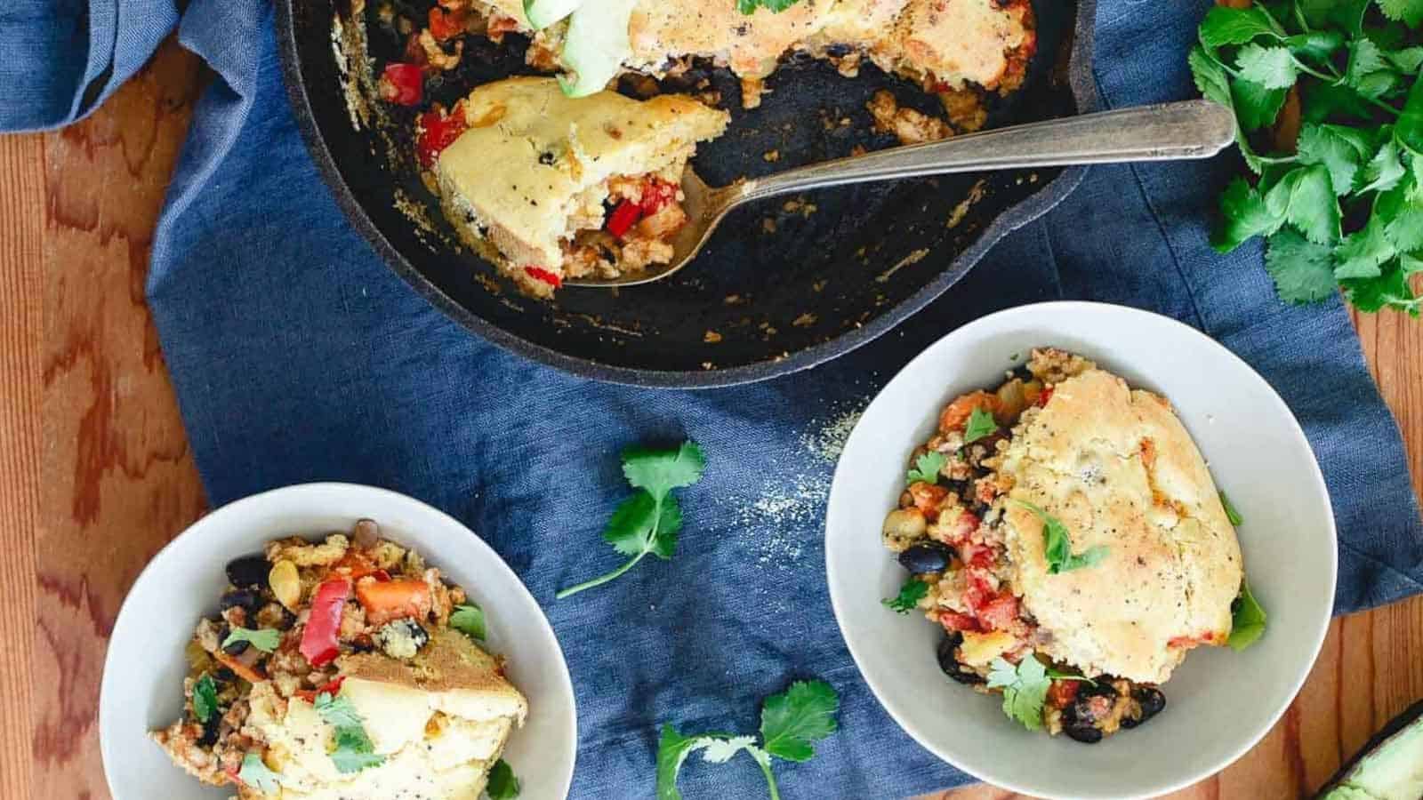 Turkey chili pie in a skillet and serving bowls.