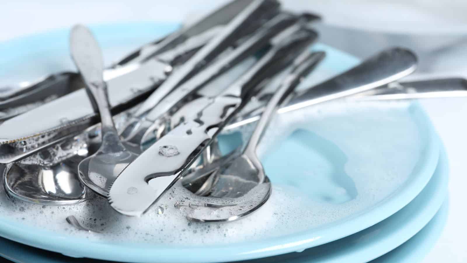Forks, knives, plates, and spoon in foam, closeup.