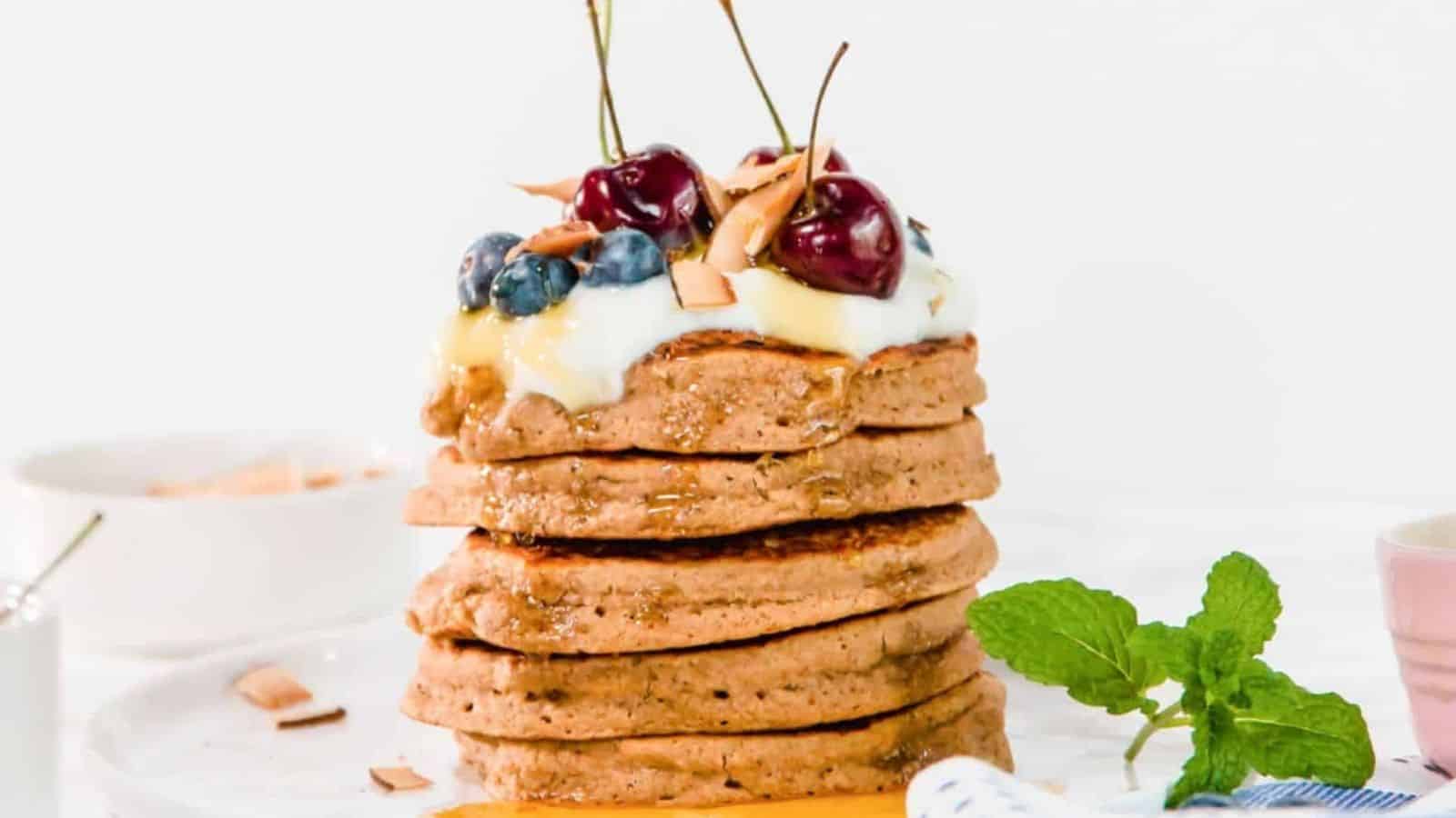 A stack of vegan oatmeal pancakes with fruit toppings.