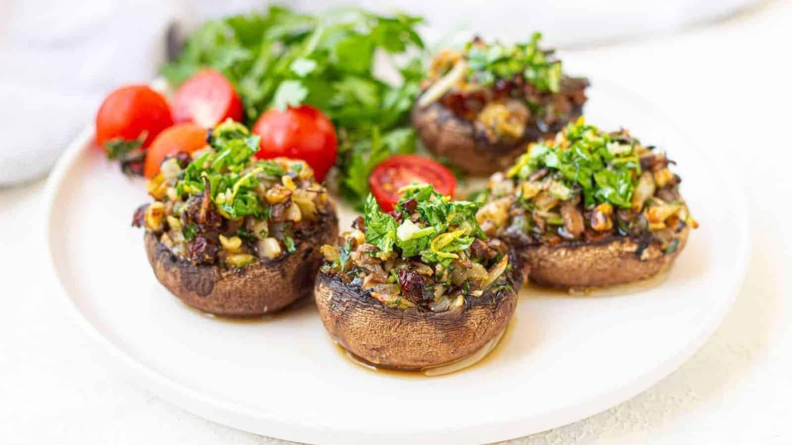 A white plate with vegan stuffed portobello mushrooms garnished with cherry tomatoes and parsley.