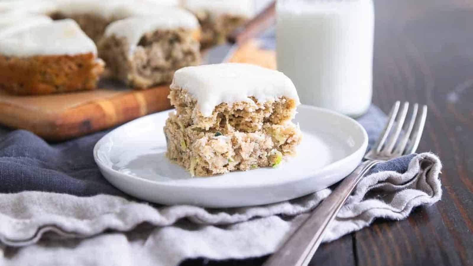 A zucchini bar with cream cheese frosting on a plate.