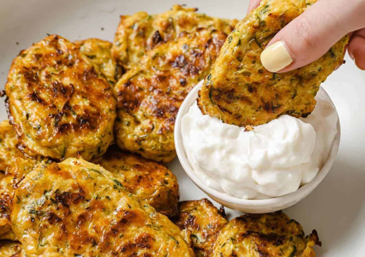 A zucchini bite being dipped into a dipping sauce.