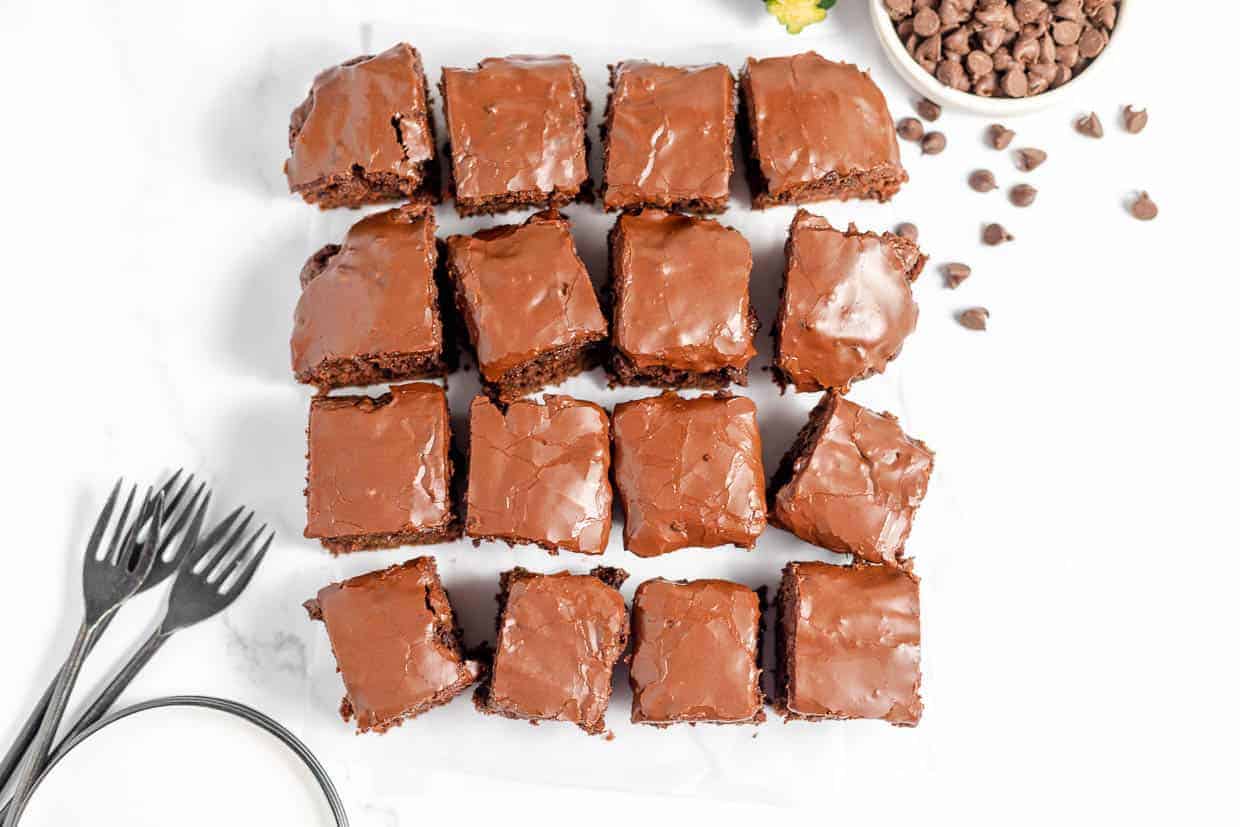 Chocolate brownies on a white plate with a knife and fork.