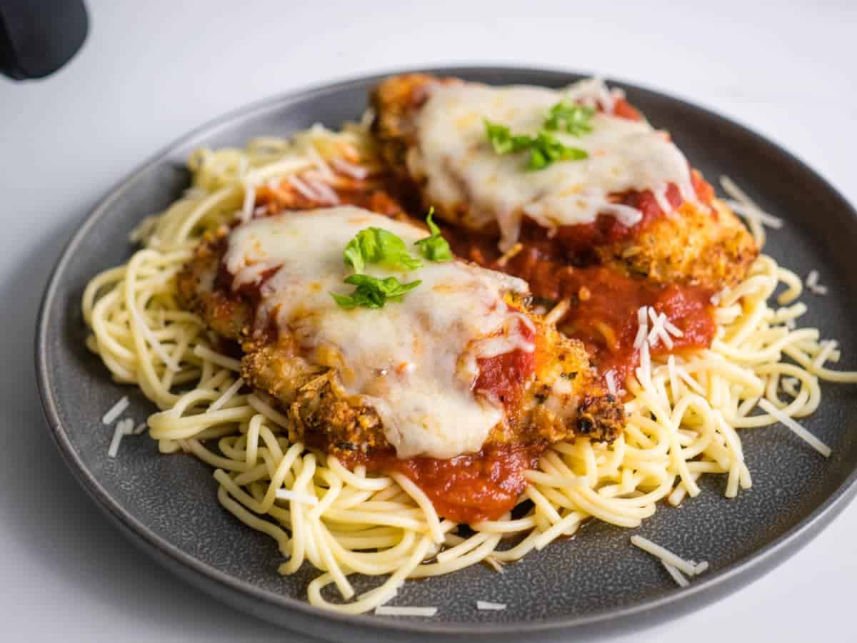 Pieces of chicken on a plate of spaghetti.