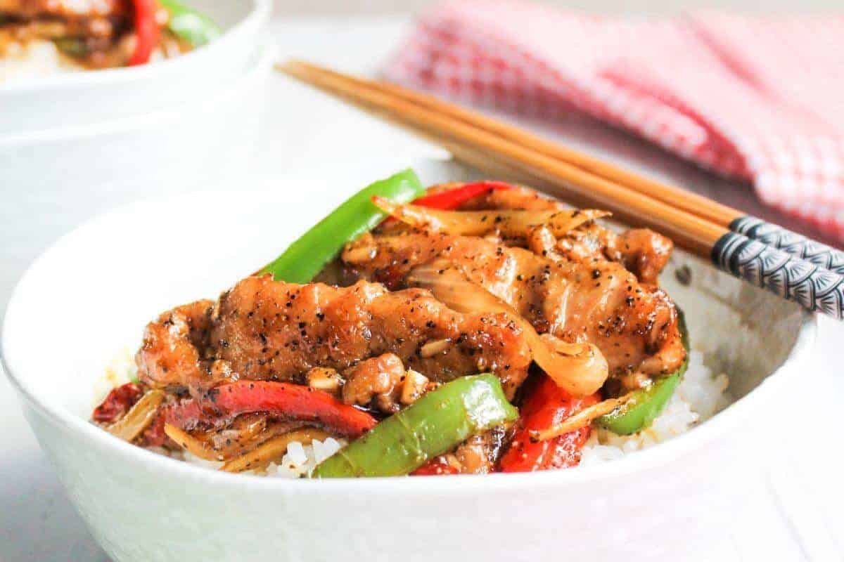 Bowl of black pepper chicken with chop sticks.