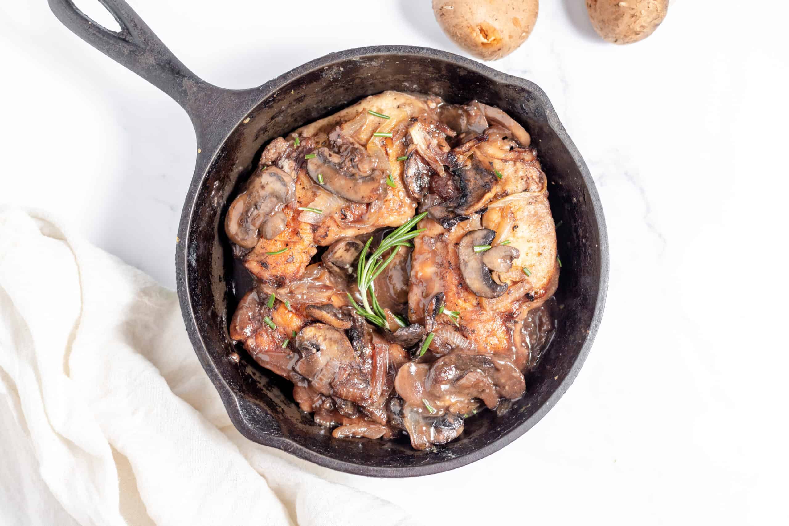 Roasted chicken with mushrooms and potatoes in a cast iron skillet.