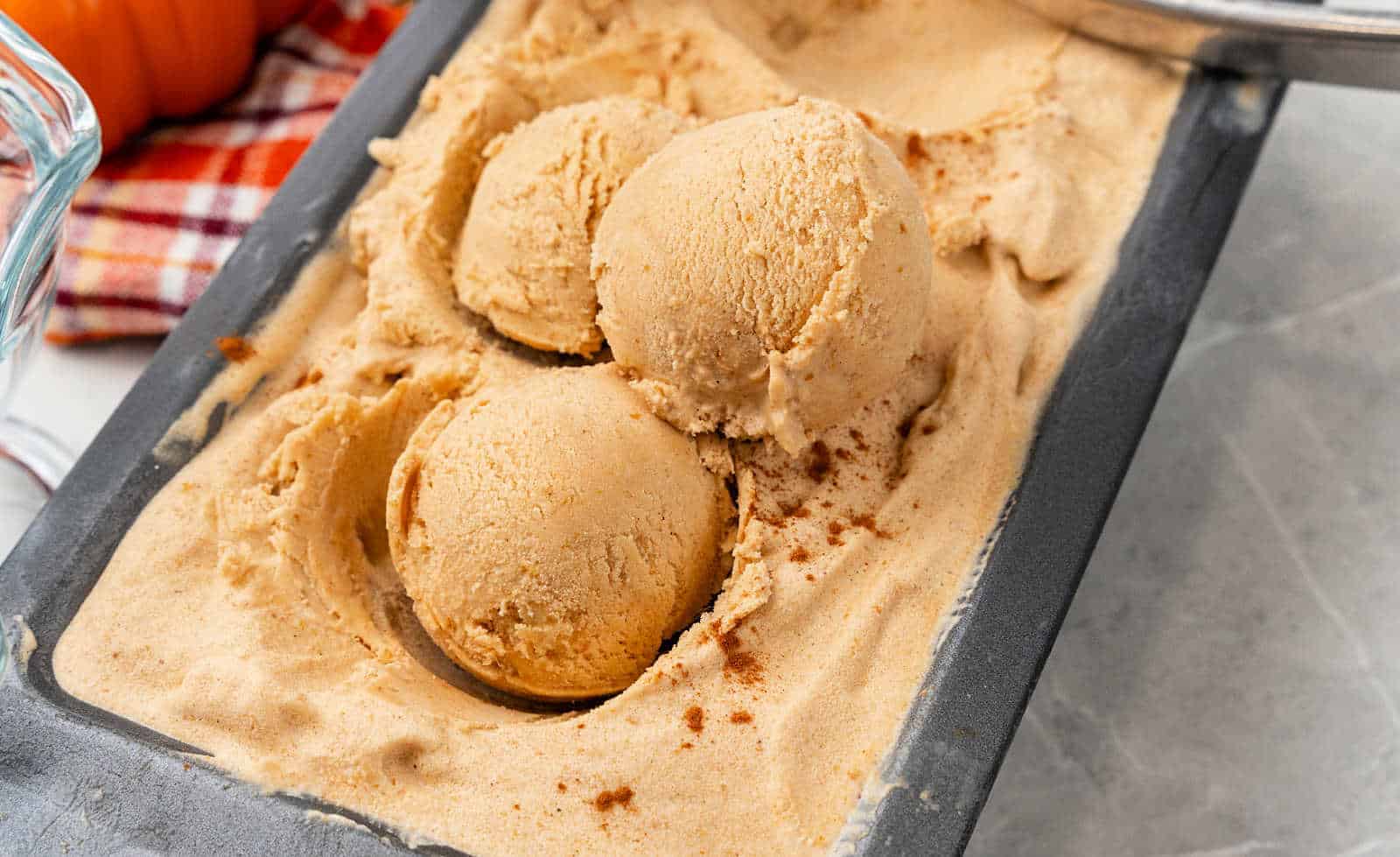 An orange bowl with pumpkin ice cream scoops.