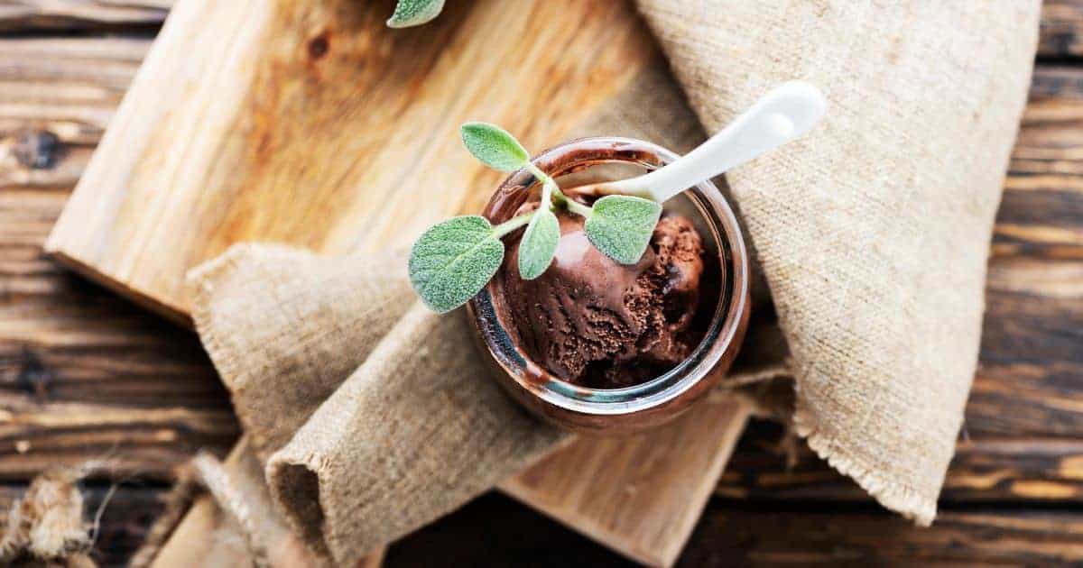 Chocolate sage ice cream in glass cup from above sage garnish burlap napkin.