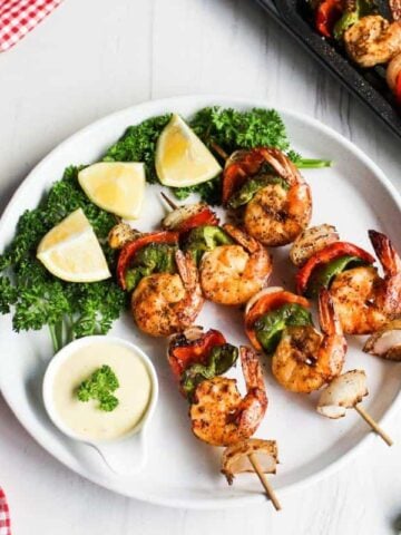 Shrimp skewers on a plate with lemon wedges.