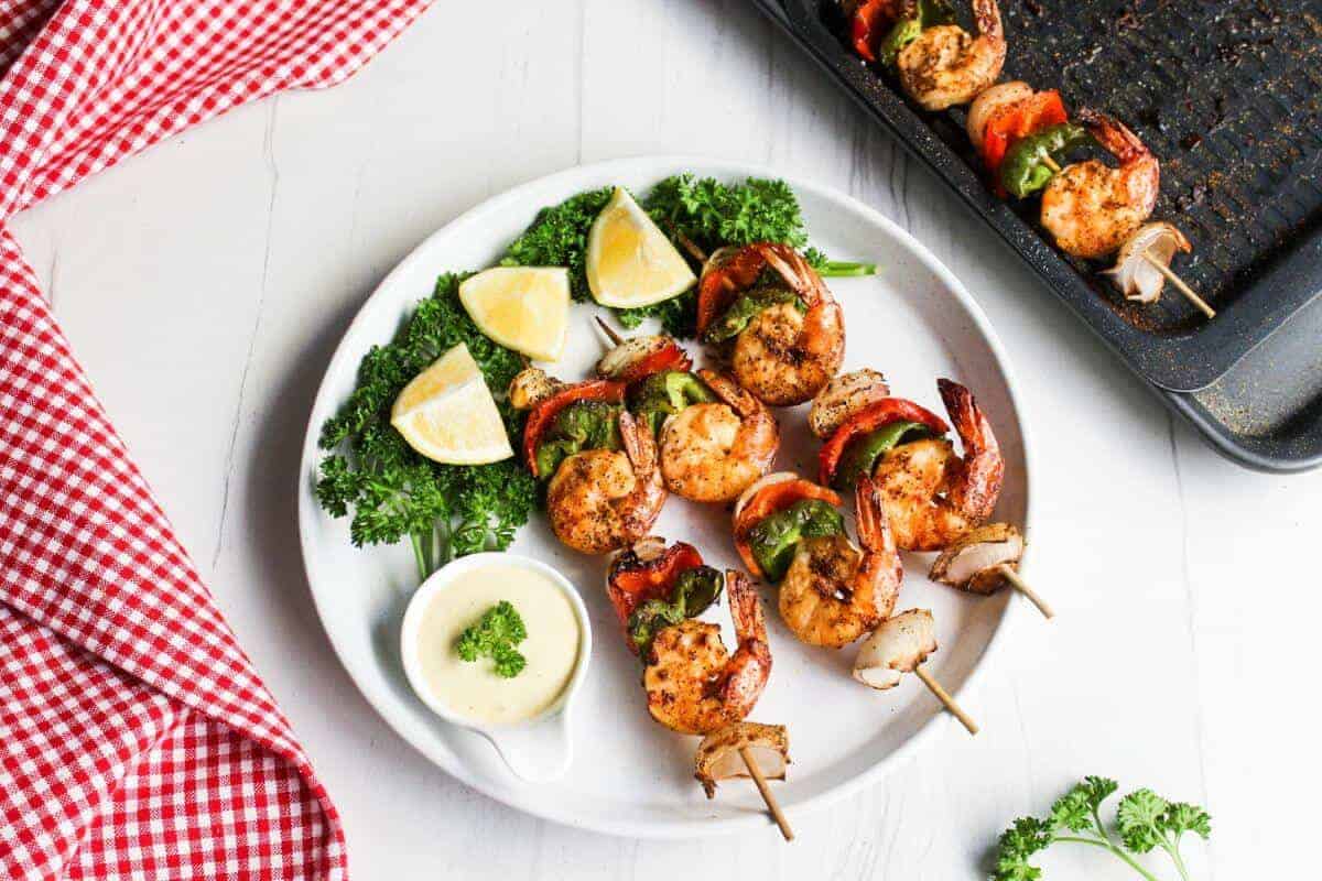 Shrimp skewers on a plate with lemon wedges.