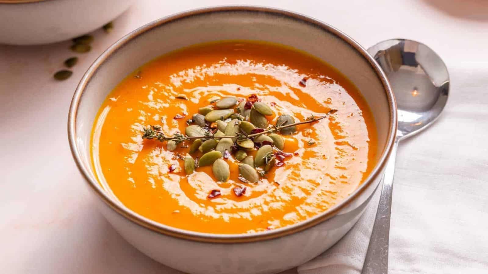 An image of acorn squash soup in a bowl garnished with thyme.