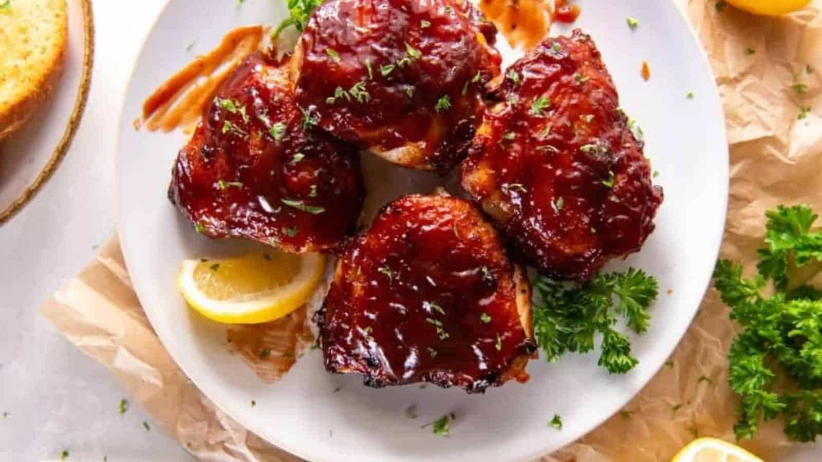 Overhead image of air fryer bbq chicken thighs with garnishes on a plate.