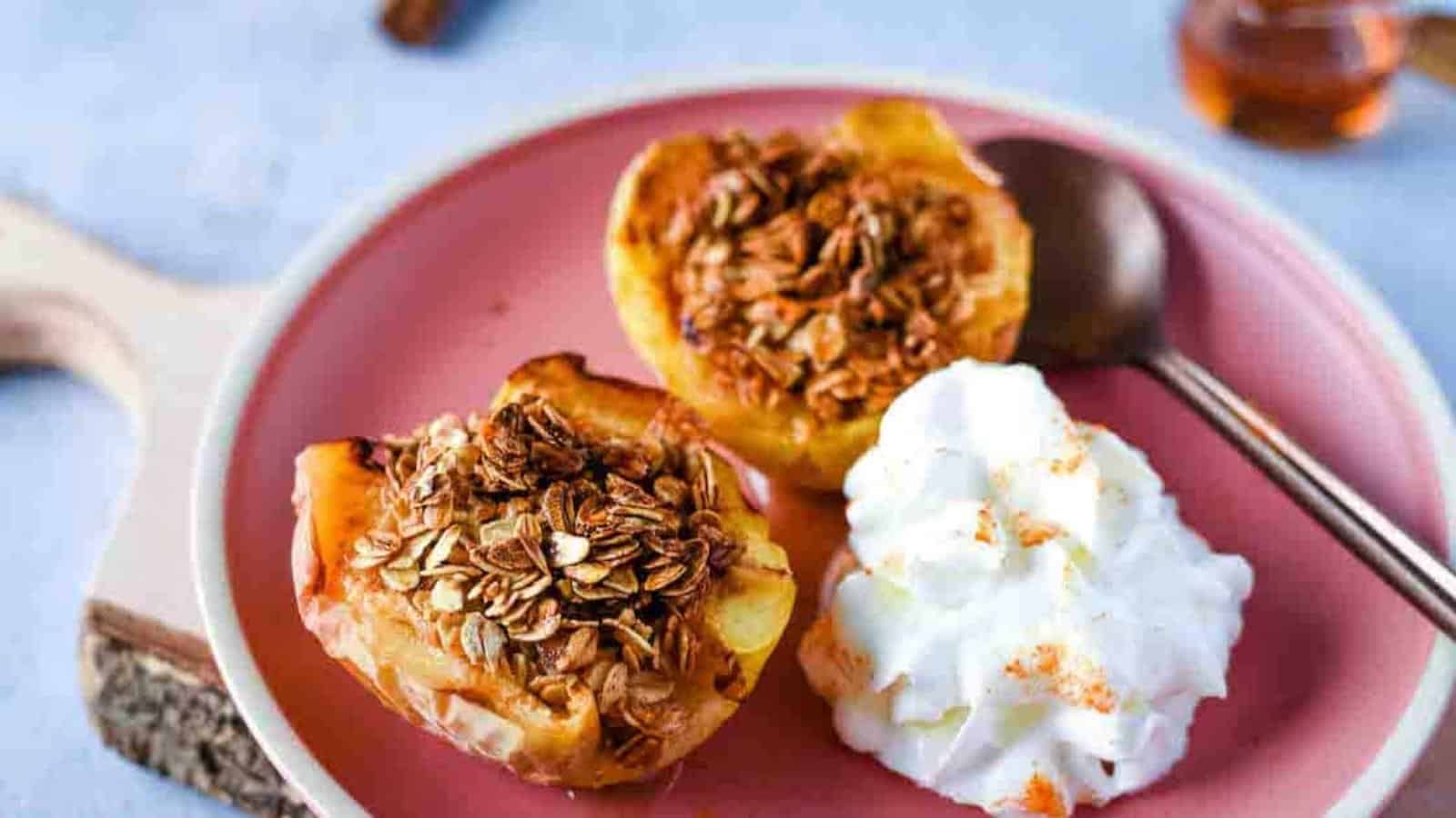 Air fryer baked apples are shown on a pink plate with whipped cream.