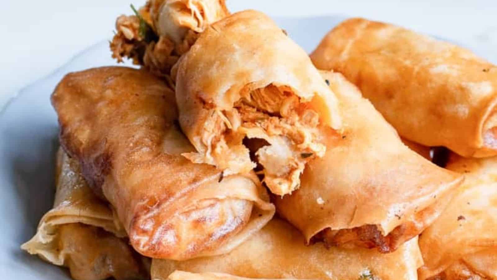 Close-up image of air fryer buffalo chicken egg rolls on a white plate.