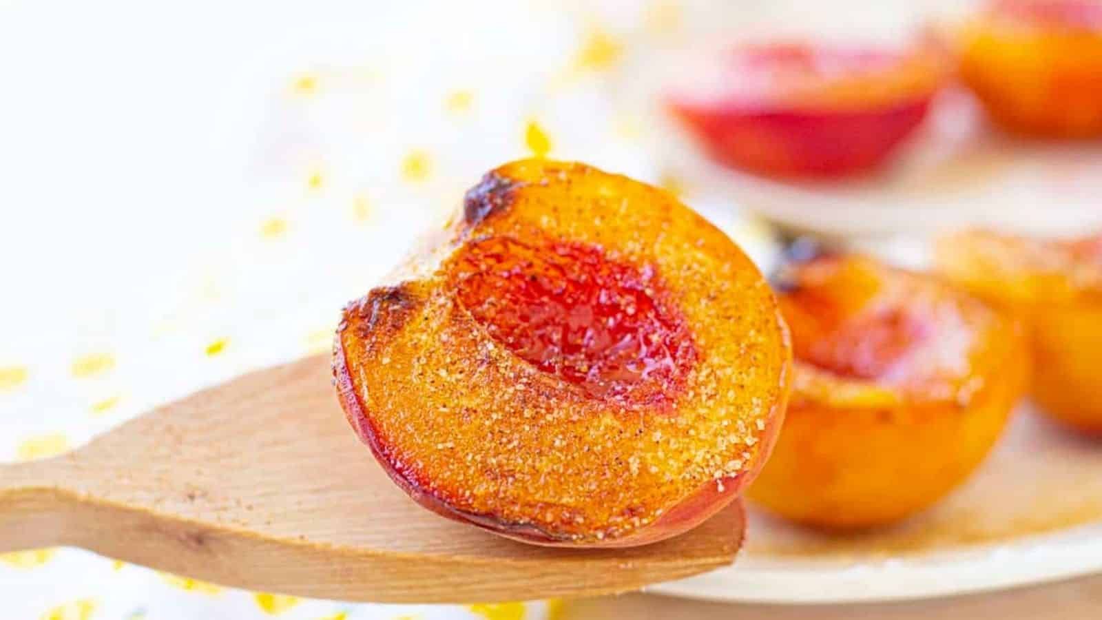 Air-fried peaches on a plate with a wooden spoon.