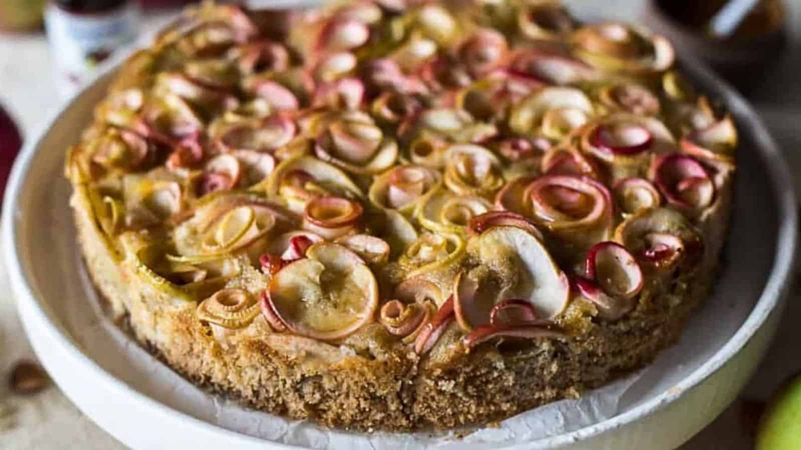 A cake with apples on top of a white plate.