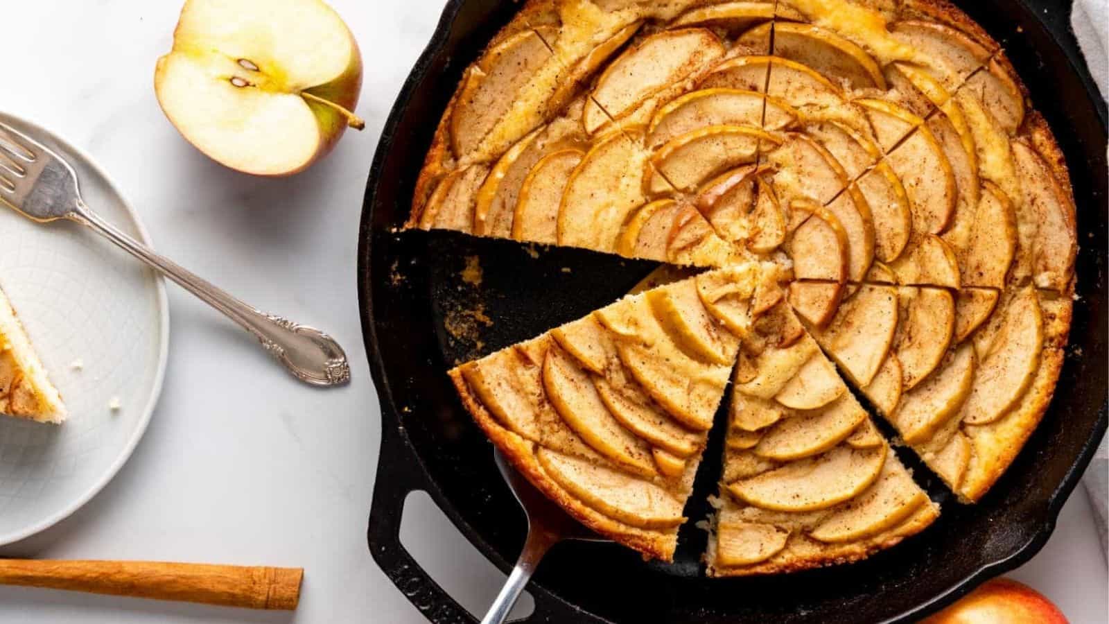 An apple cake baked in a cast iron skillet, cut into slices.