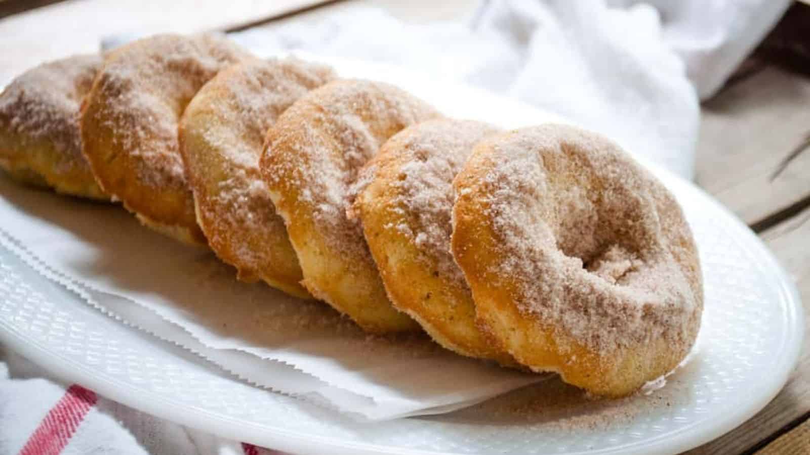 Six apple cinnamon baked doughhnuts on a white plate.