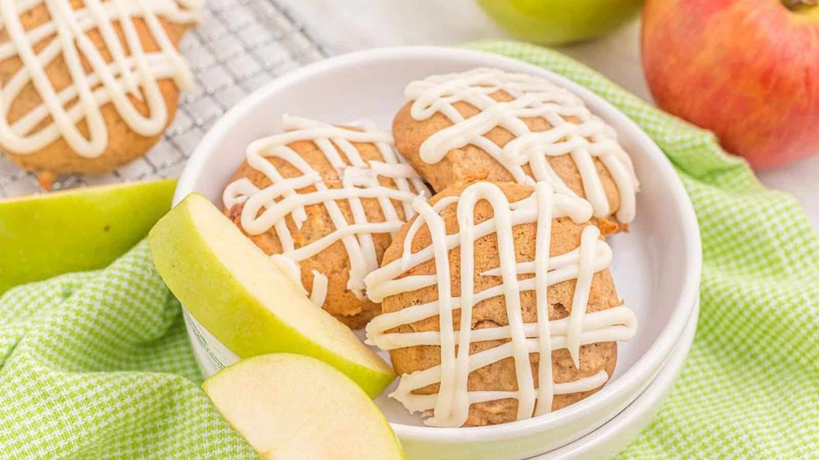 Three pieces of apple pie muffin top cookies with vanilla maple glaze on a plate.