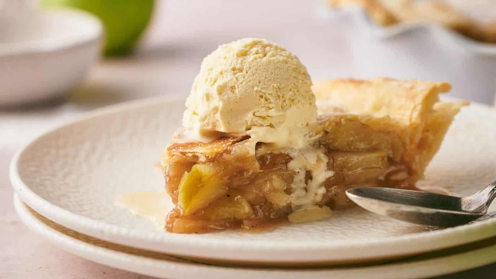 A slice of apple pie on a plate with a scoop of ice cream.