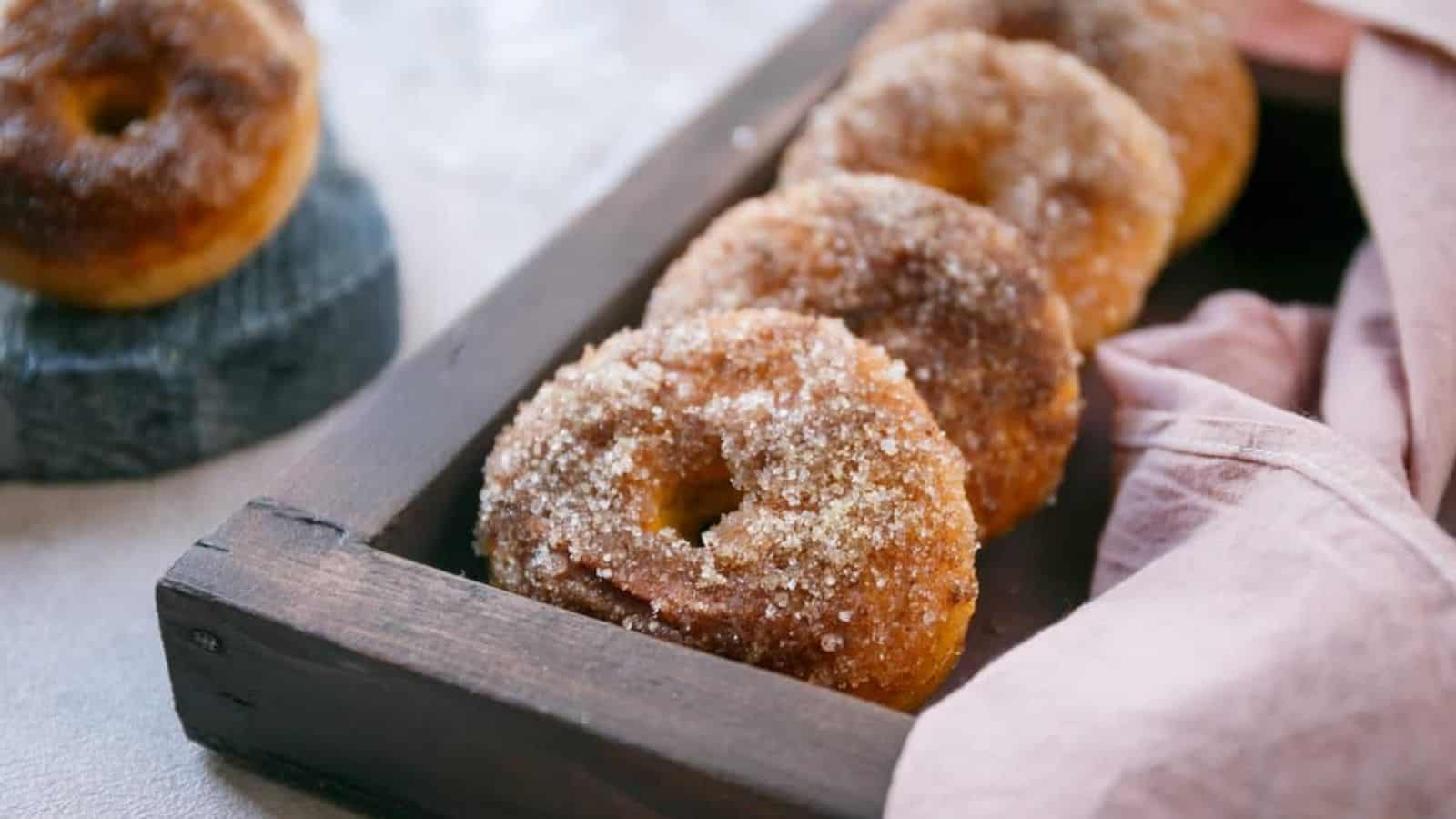 Four baked pumpkin donuts in a tray.