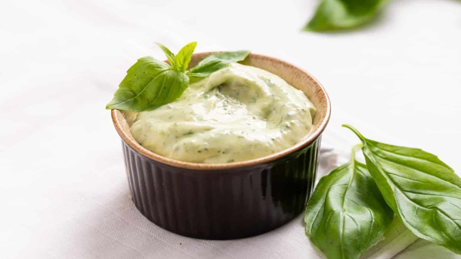 An image of creamy basil aioli in a bowl, garnished with a fresh basil leaf.