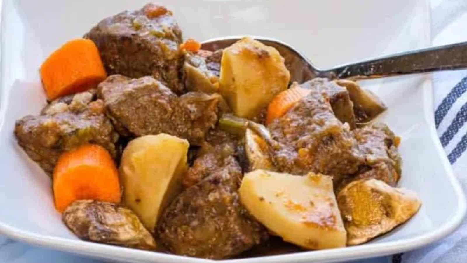 Close-up image of beef stew with a spoon in a plate.