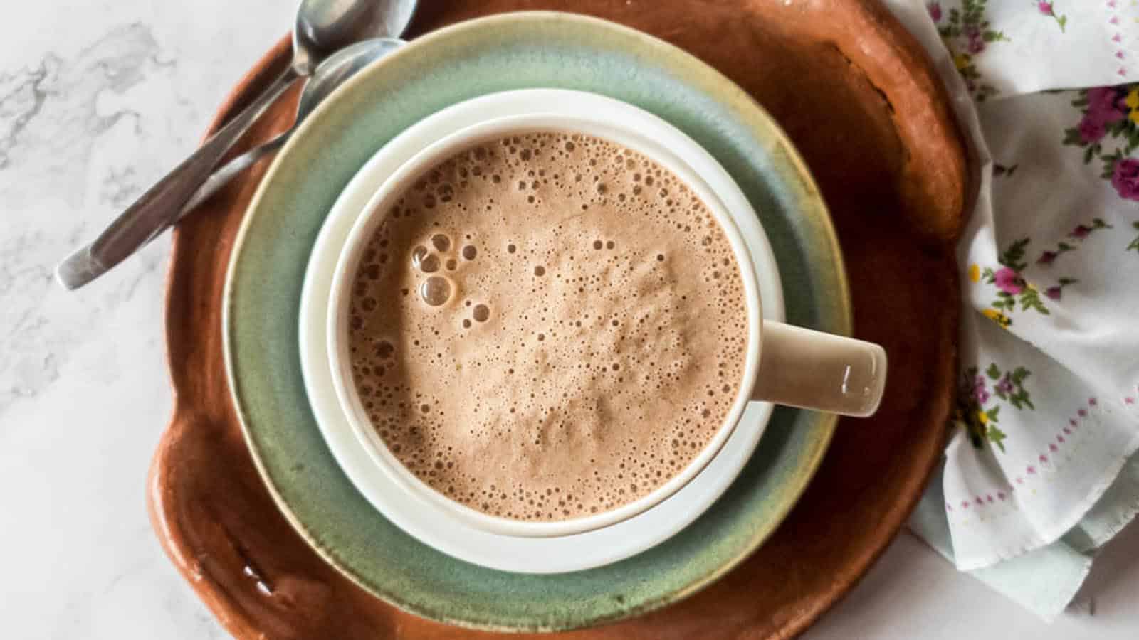 A picture of bone broth latte in a mug with saucer, plate and tray.