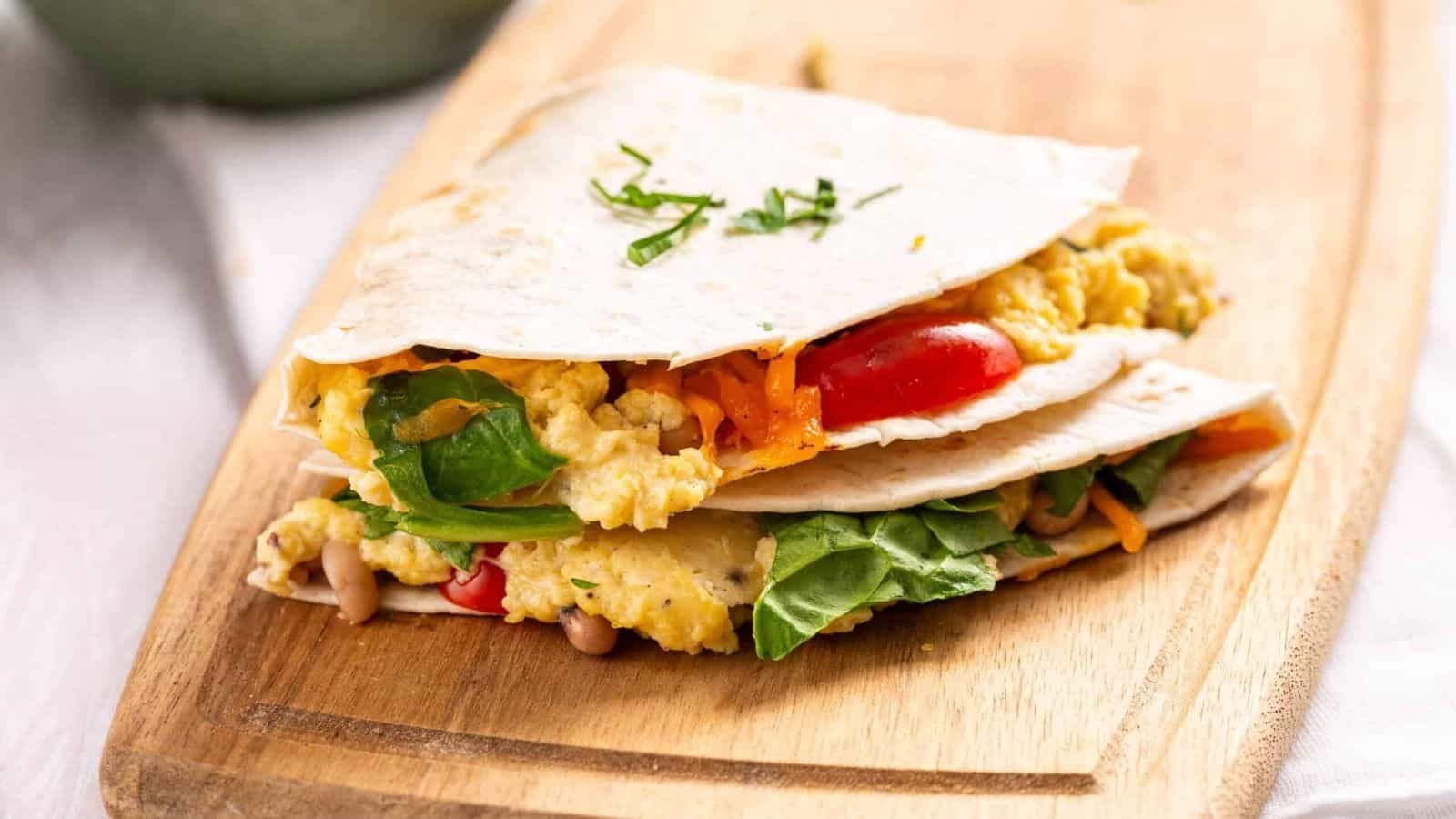 An image of two breakfast quesadillas on a wooden cutting board.