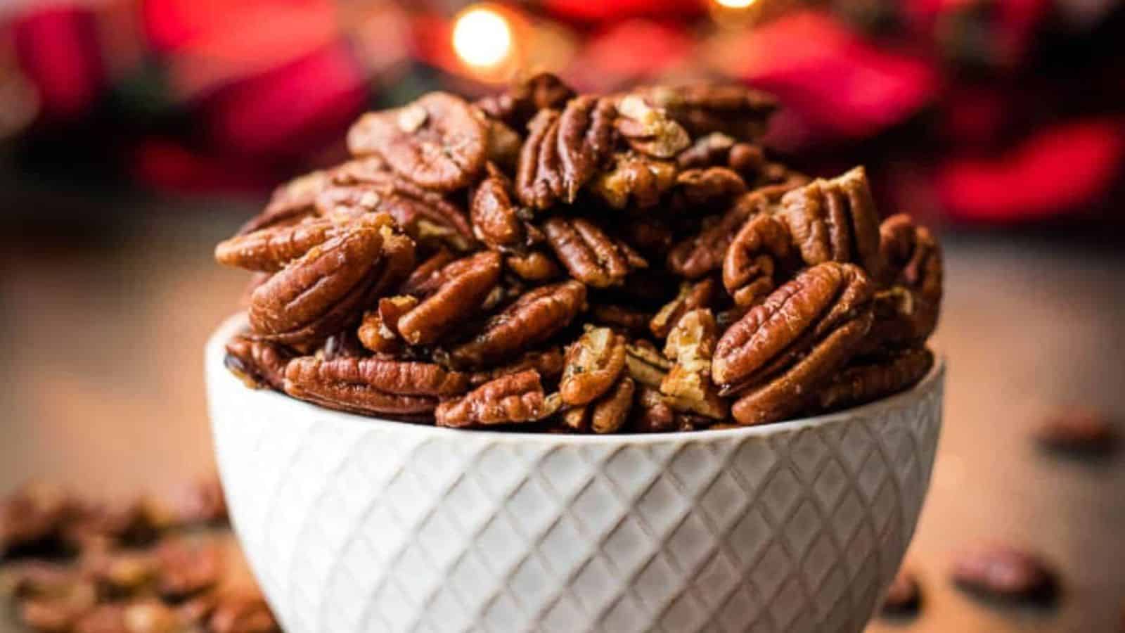 Three bowls of brown butter roasted pecans on a gray background next to a red tartan cloth.