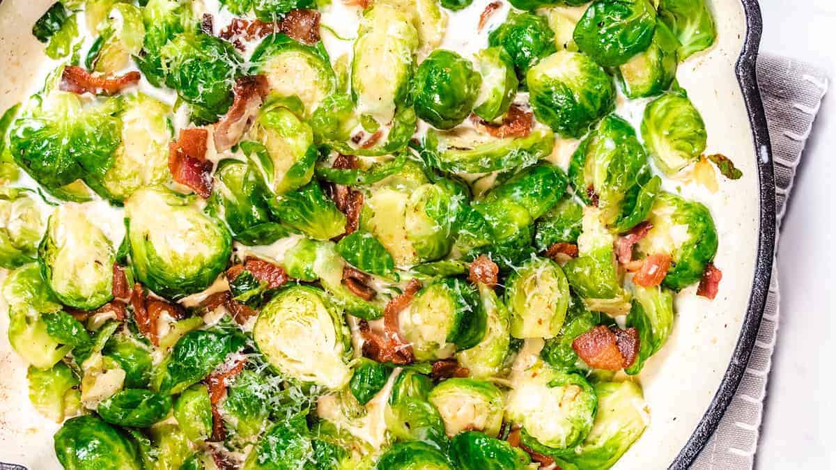 A pan with brussels sprouts and bacon in a cream sauce.