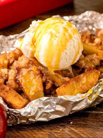 Campfire Apple Crisp on a foil with a scoop of ice cream on top.