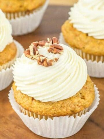 Close-up image of carrot cake cupcakes on a wooden surface.