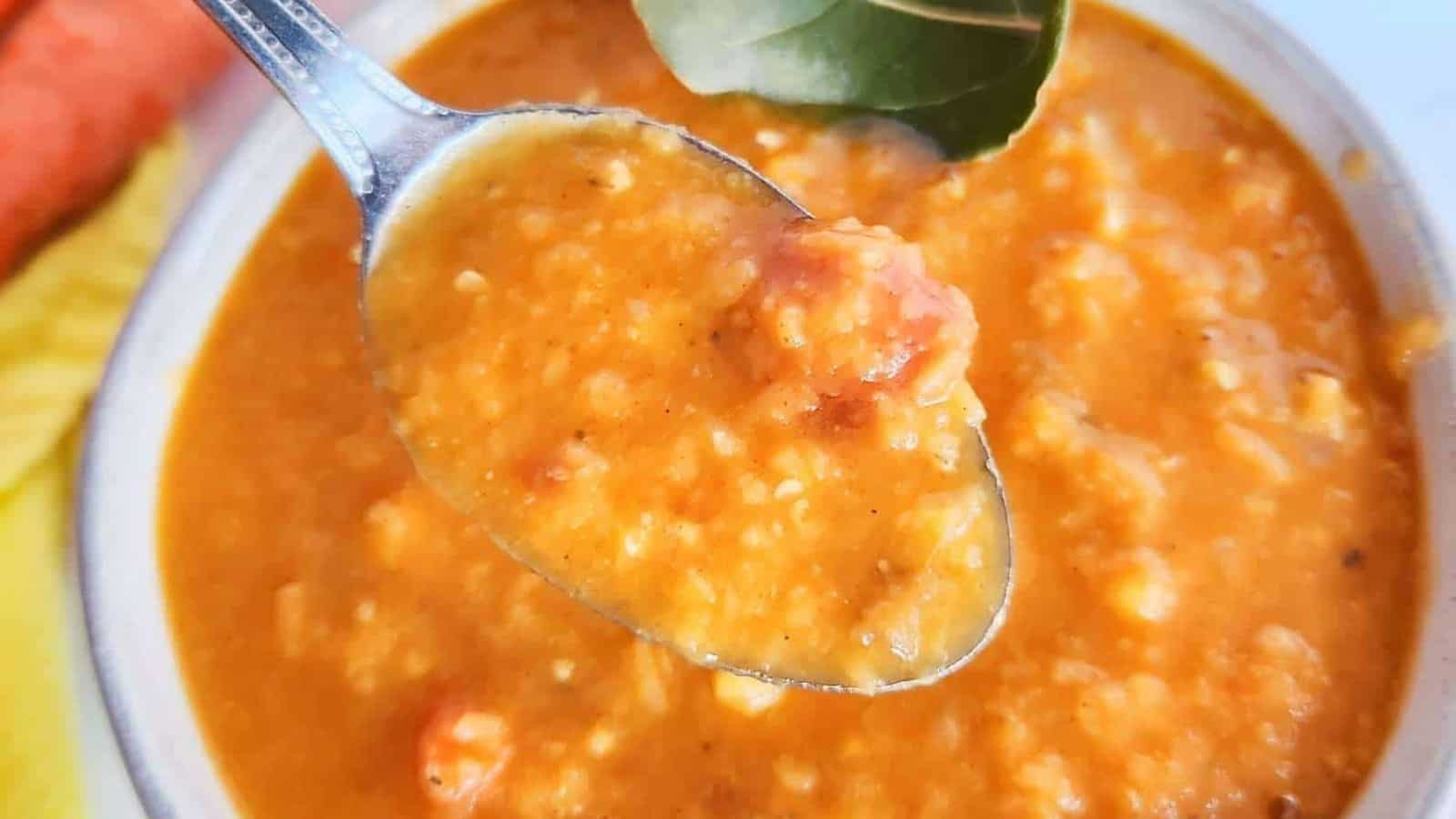 A spoonful of carrot and red lentil soup in a bowl.