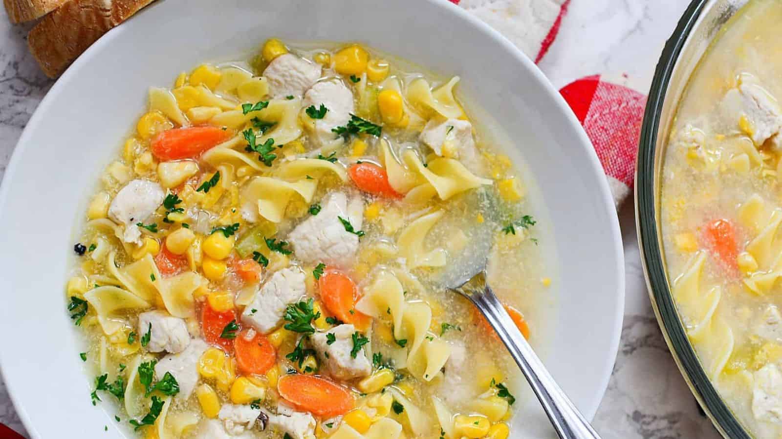 Chicken corn noodle soup in bowl with spoon.