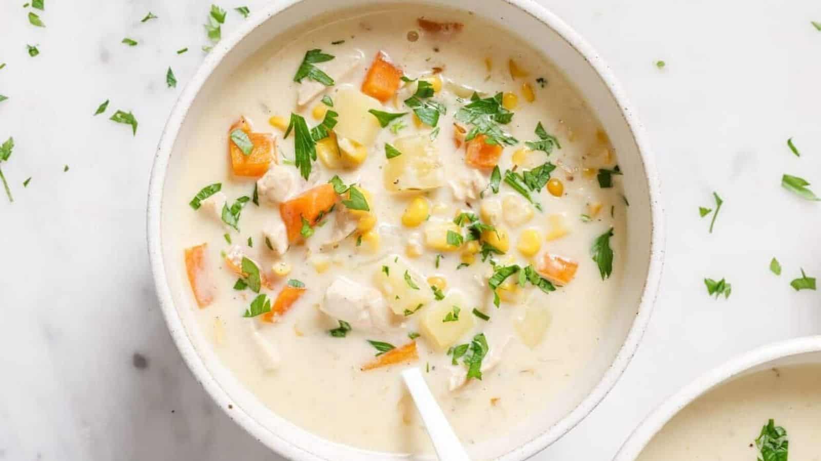 Two bowls of chicken corn soup garnished with parsley.