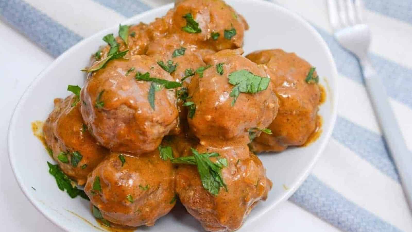 Chicken meatballs in a white bowl with a fork.