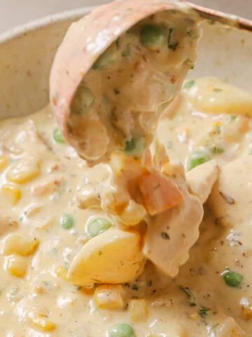 Chicken pot pie soup in a white bowl with a spoon.