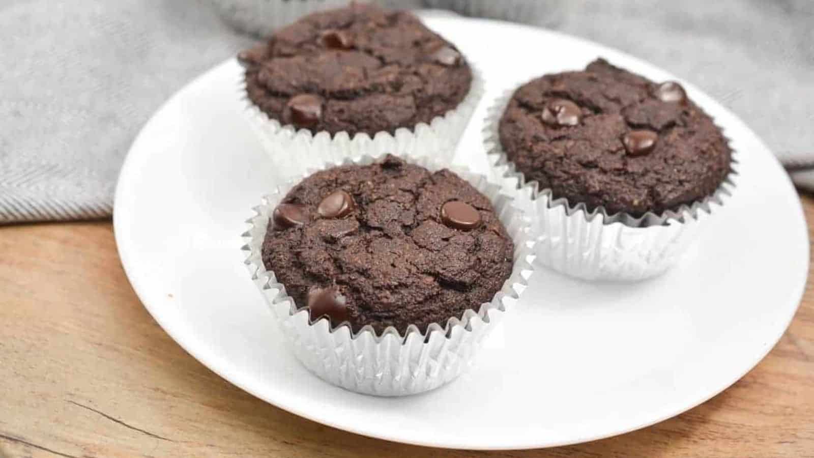 Three chocolate muffins on a white plate.