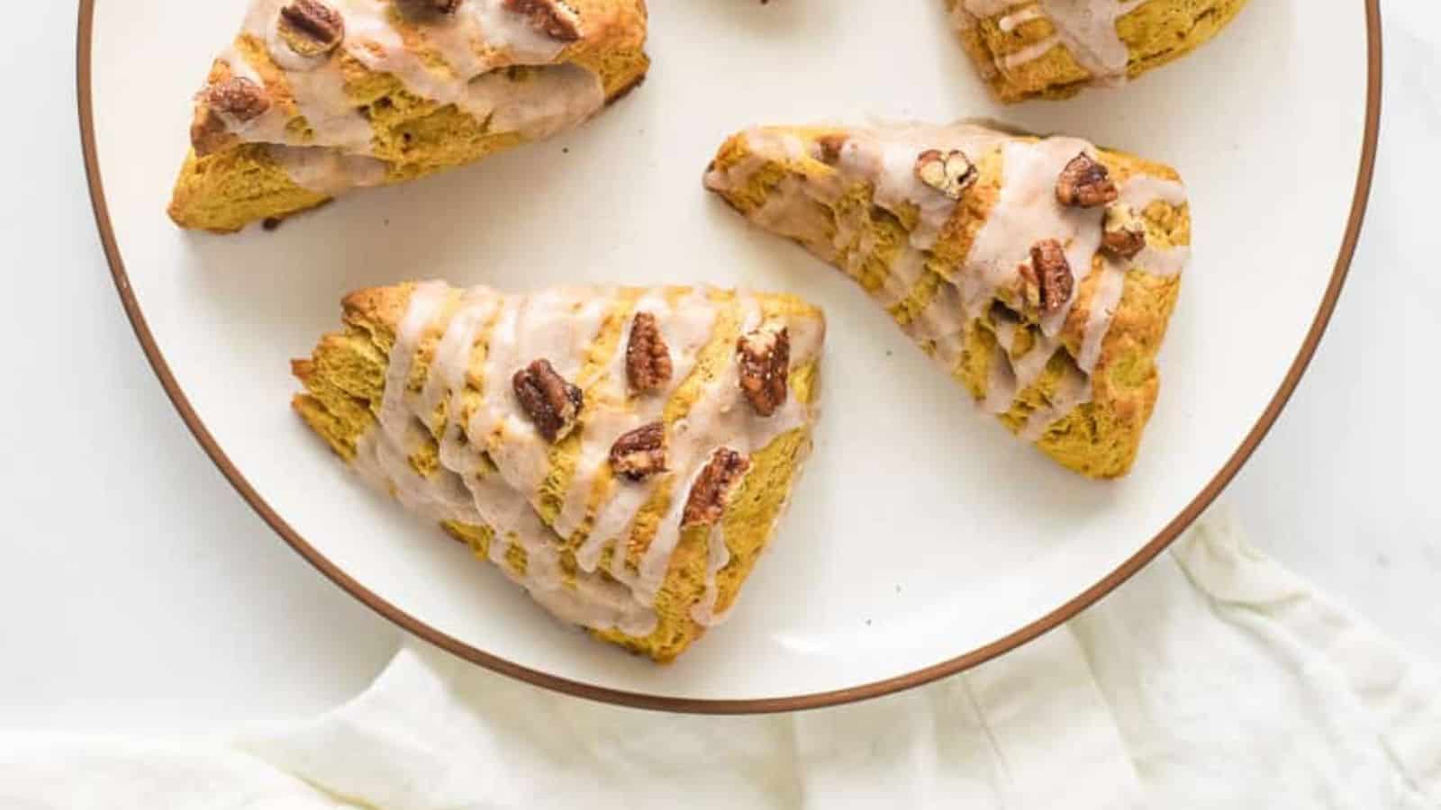 A plate of Cinnamon Glazed Pumpkin Scones with Candied Pecans.