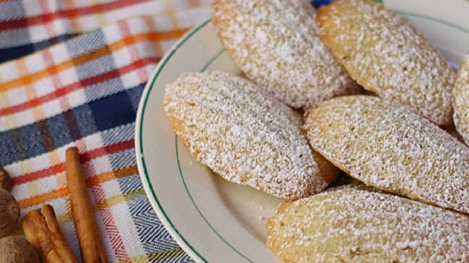 A plate with madeleine cakes sprinkles with powdered sugar.