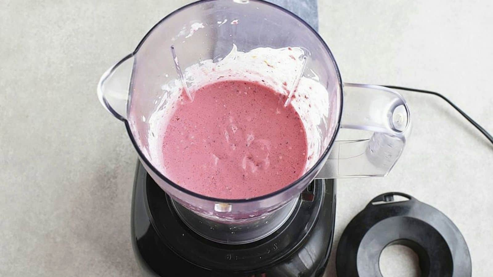 Top view of an open blender with pink smoothie.