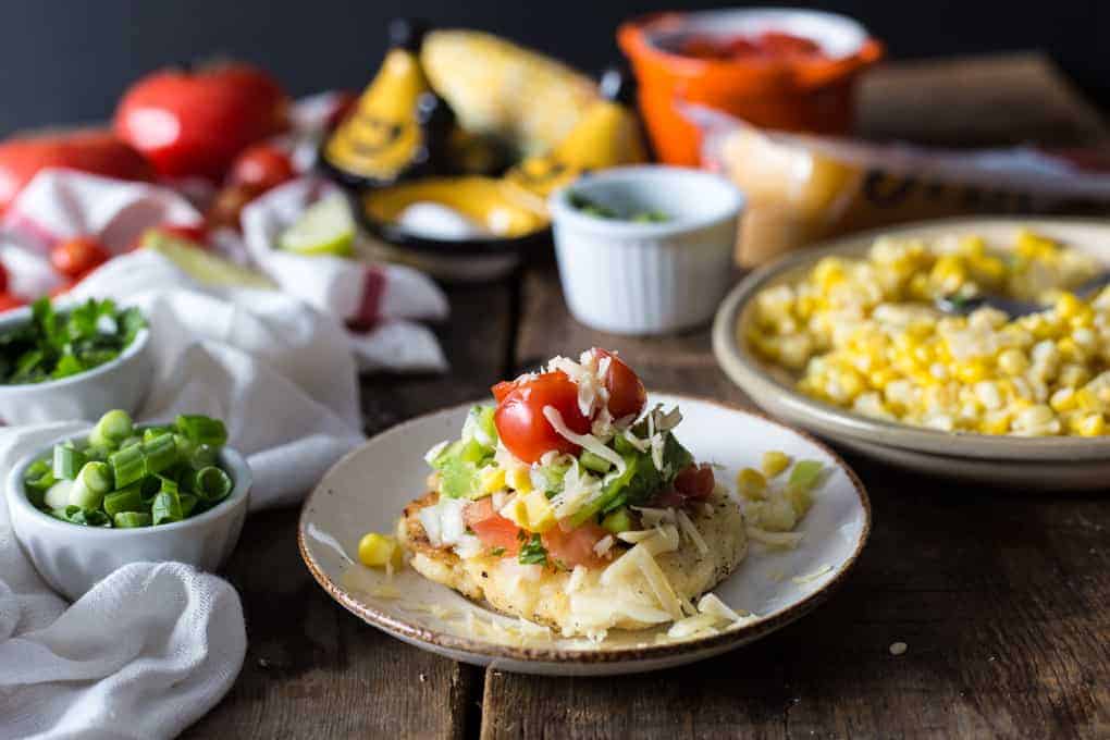 Cheese arepa on a plate with toppings.