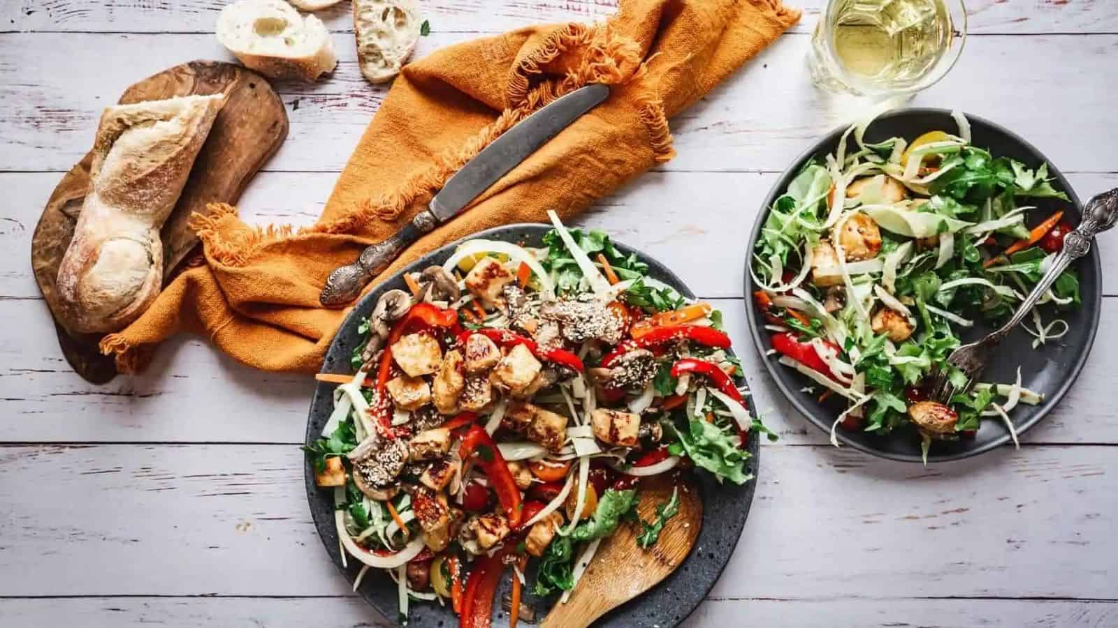 Large plate of fried halloumi salad with wine glass.