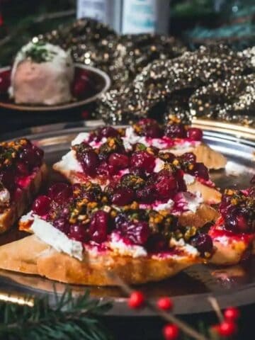 Cranberry goat cheese bruschetta with garlic herb chermoula on a plate.