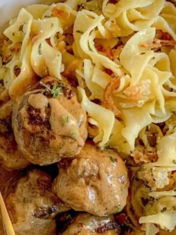 A bowl filled with French onion noodle casserole and a side of meatballs.