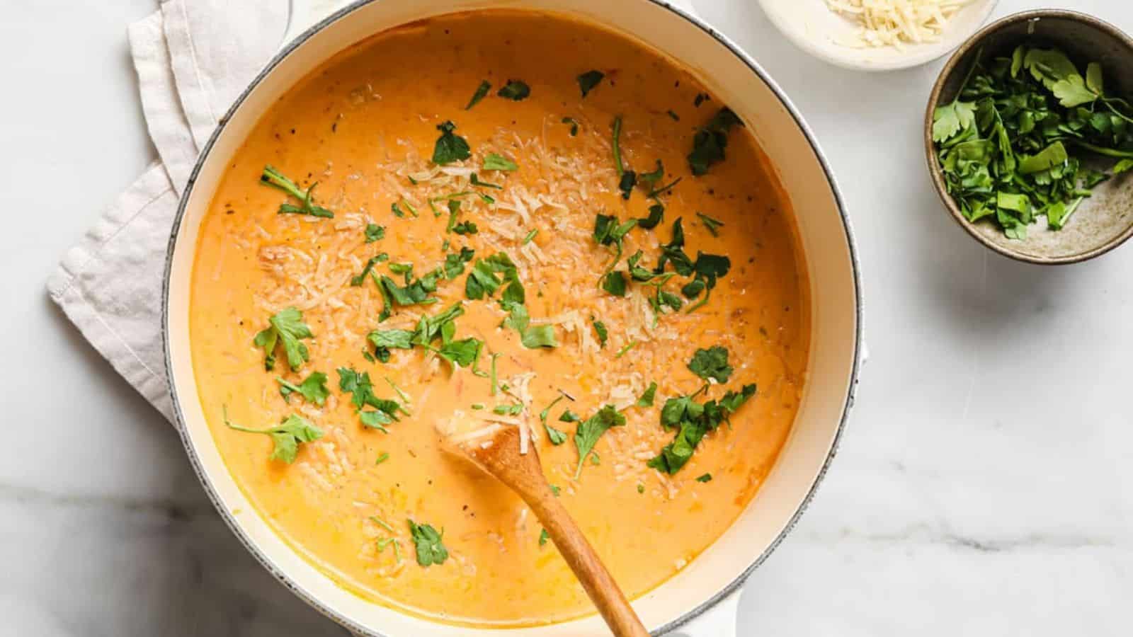 Creamy Italian sausage soup in a pot with a spoon and garnishes on the side.