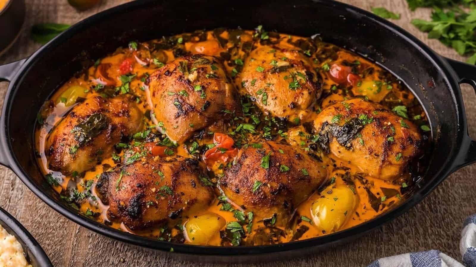 Creamy lemon chicken thighs on a black plate.