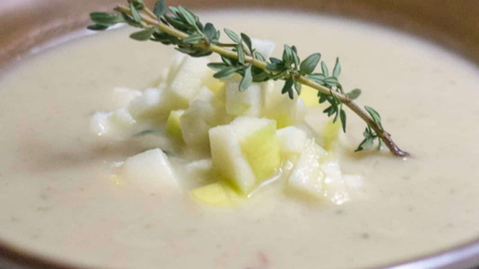 A bowl of soup with apples and sprigs of thyme.