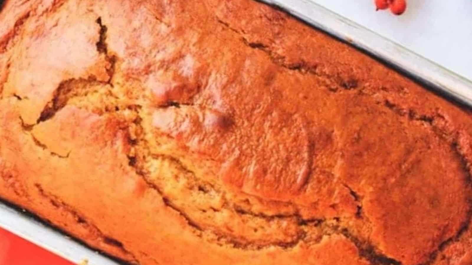 A loaf of pumpkin bread in a pan with cinnamon sticks.